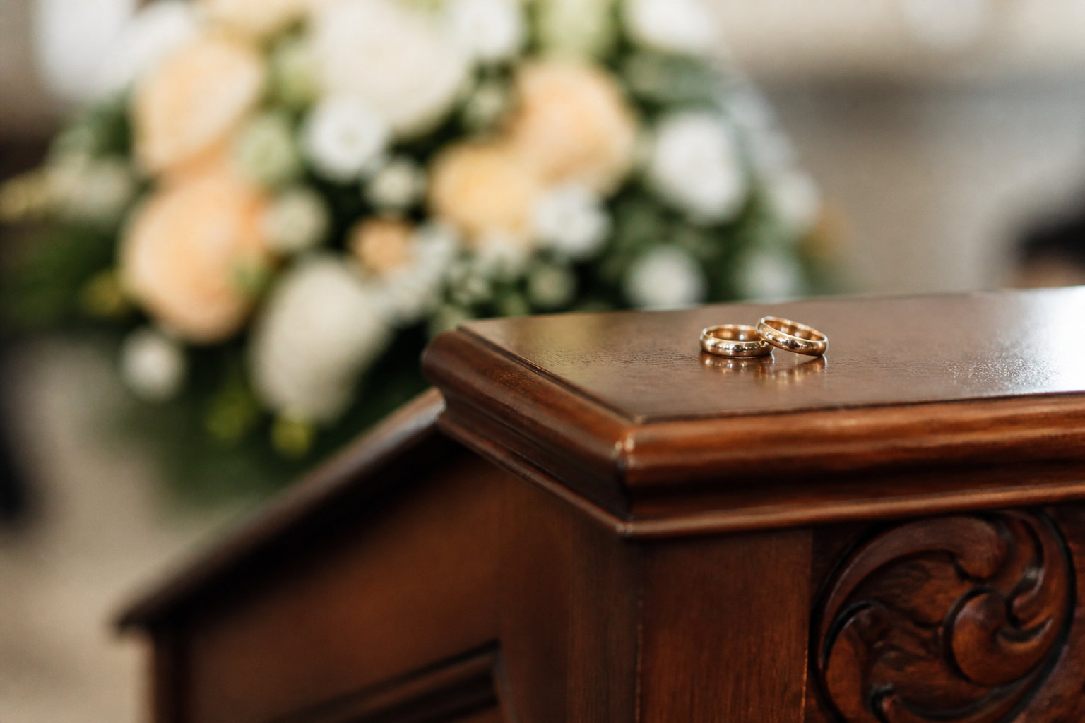 Alliances de mariage posées sur un pupitre en bois avant la cérémonie