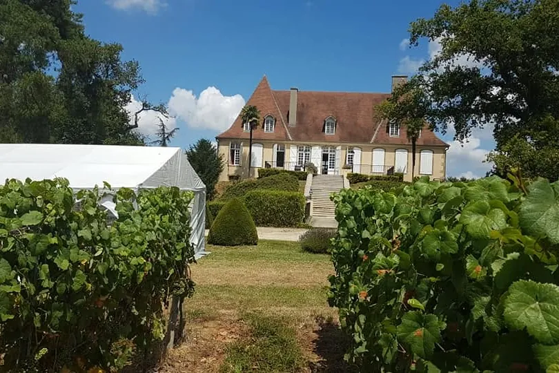Château de Crouseilles vu depuis les vignes, avec un chapiteau de réception installé dans le parc pour un mariage