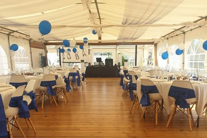 Chapiteau du Château d’Orleix décoré en bleu et blanc pour un mariage, parquet et régie DJ au fond
