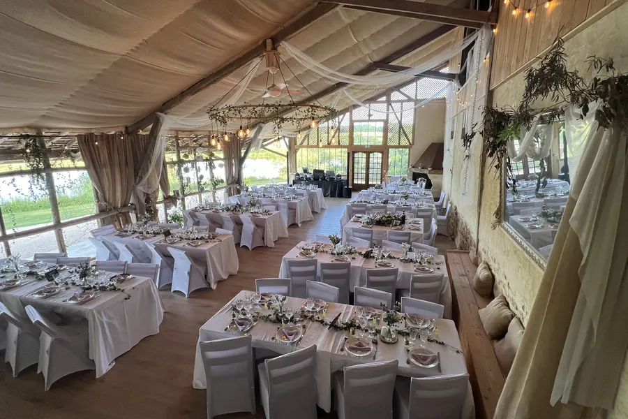 Grange du Clos du Gaja à Troncens dressée pour un mariage, lustre végétal, vue sur le lac et régie DJ au fond