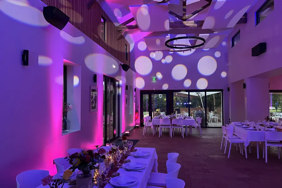 Salle de réception du Domaine de Barthas mise en lumière pour un mariage, tables dressées et projections lumineuses
