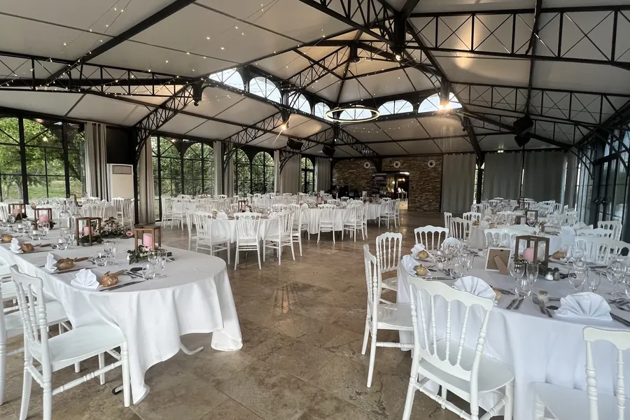 Orangerie vitrée du Domaine de la Métairie à Ossun dressée pour un mariage, charpente métallique et vue sur le parc