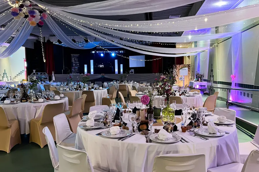 Salle des fêtes de Barbazan-Debat habillée de voilages et de guirlandes pour un mariage, scène et régie DJ au fond