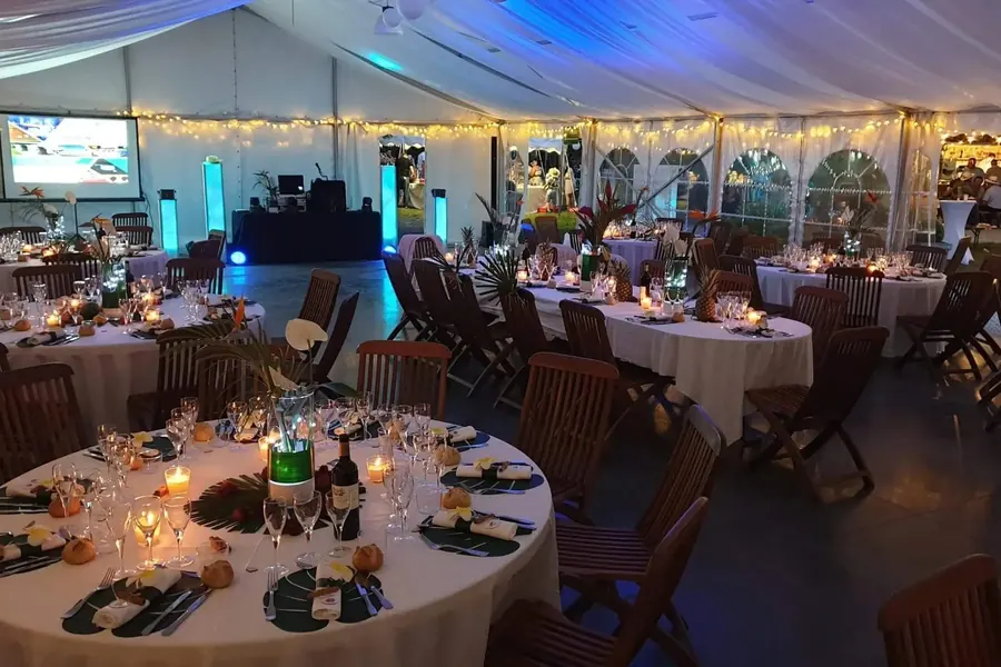 Chapiteau de la Villa Corina dressé pour un mariage, tables éclairées aux bougies et régie DJ au fond